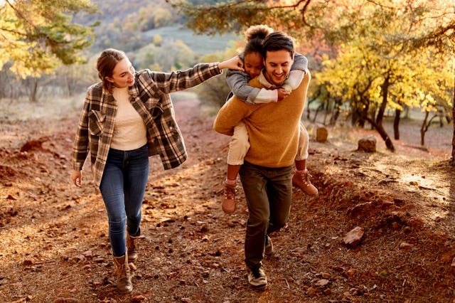 A woman gets to know her stepdaughter on a sunny autumn day outdoors, with a girl on her father's ba...