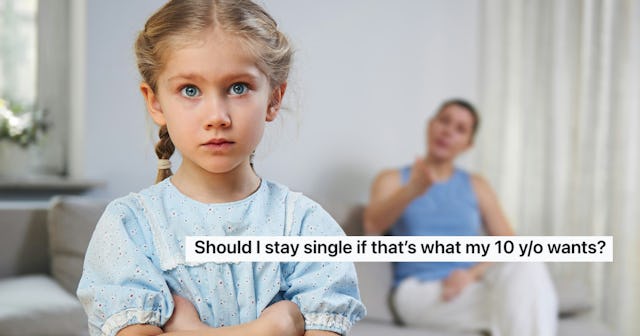 A concerned young girl with blue eyes crosses her arms, looking at the camera while a woman sits in ...