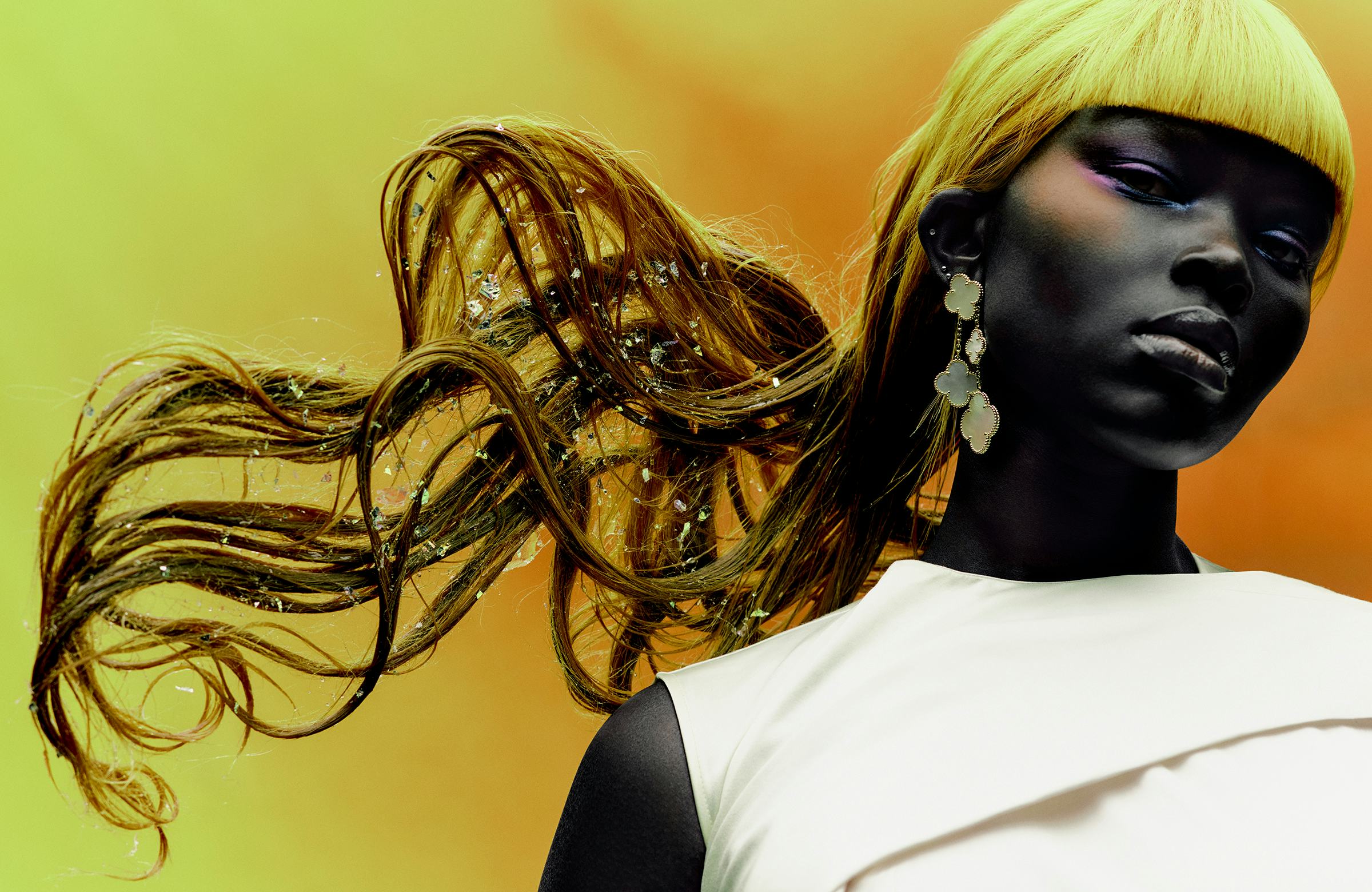 a person standing in front of a yellow wall with an artful blonde hairstyle