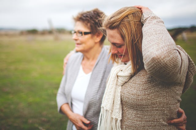 Two people walking closely in a grassy field; one with short hair and glasses, the other with long h...