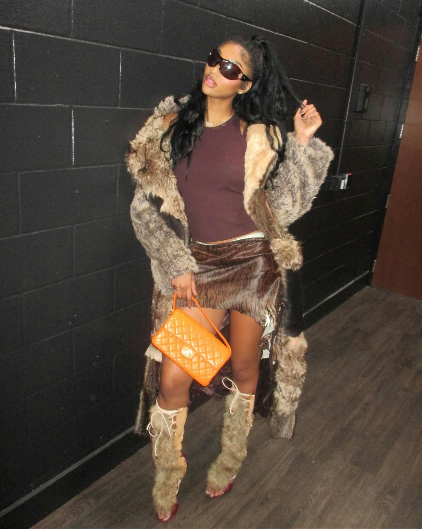 Angel Reese wears a tank top, mini, and fur coat. 