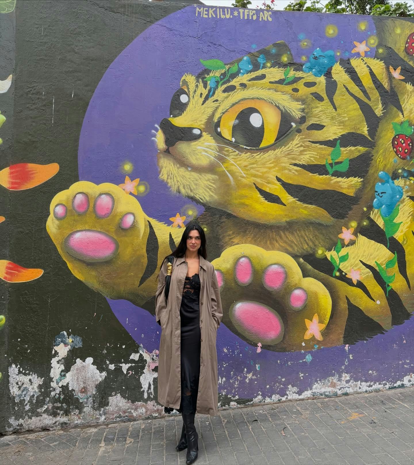 Dua Lipa wears a slip and trench.