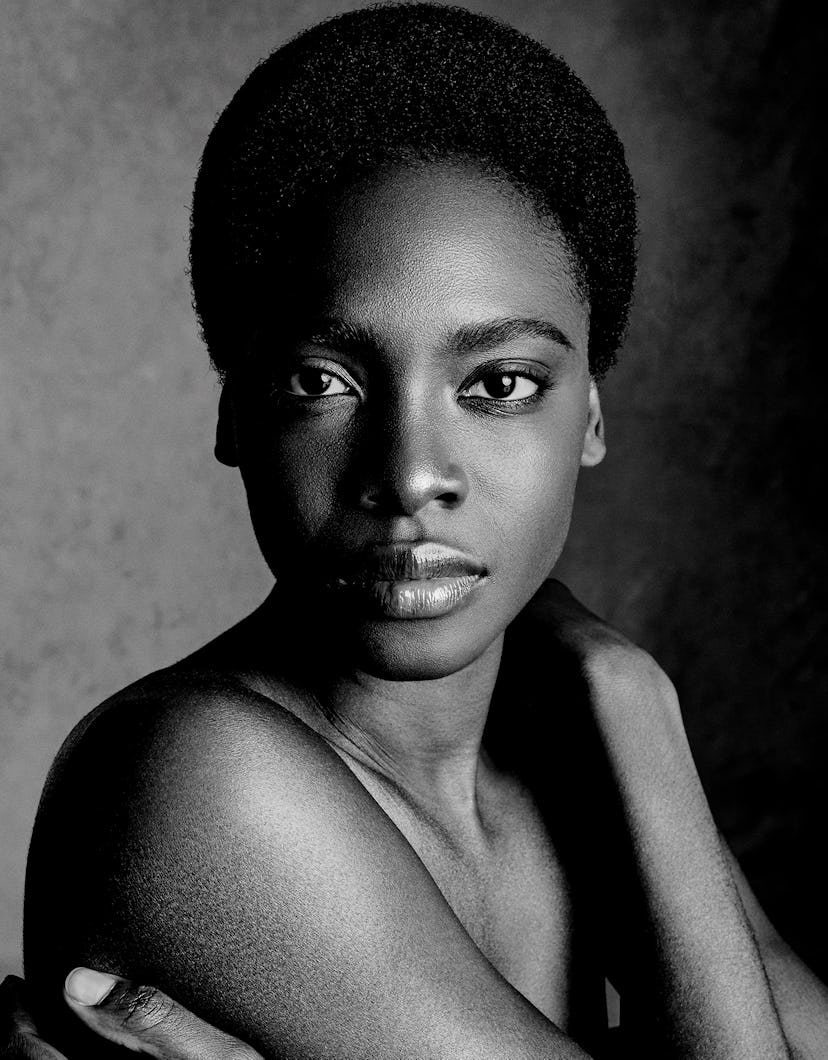 a model with short coily hair cropped close to their head, it's a beauty/glamour shot done in black ...
