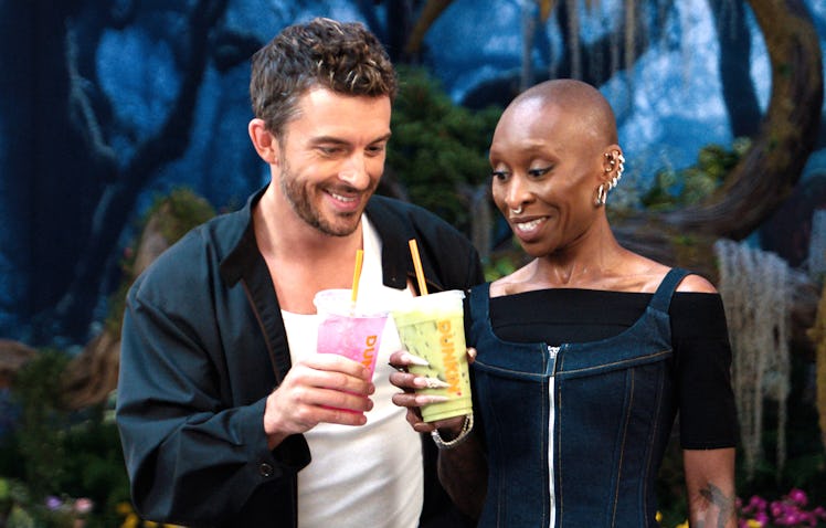 Jonathan Bailey and Cynthia Erivo cheersing with Dunkin's Wicked Pink Refresher and Green Matcha.