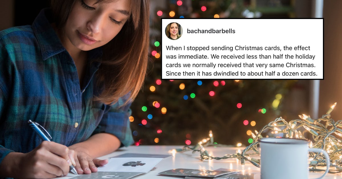 A woman writes holiday cards in front of a Christmas tree. 