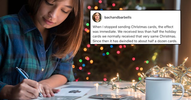 A woman writes holiday cards in front of a Christmas tree.