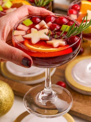 holiday punch in a cocktail glass topped with star shaped fruit, in a story about easy holiday cockt...