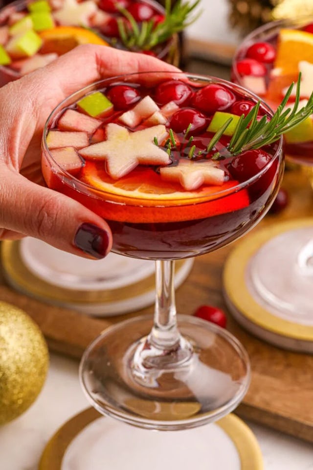 holiday punch in a cocktail glass topped with star shaped fruit, in a story about easy holiday cockt...