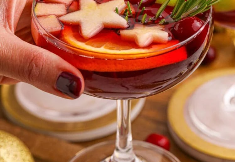 holiday punch in a cocktail glass topped with star shaped fruit, in a story about easy holiday cockt...