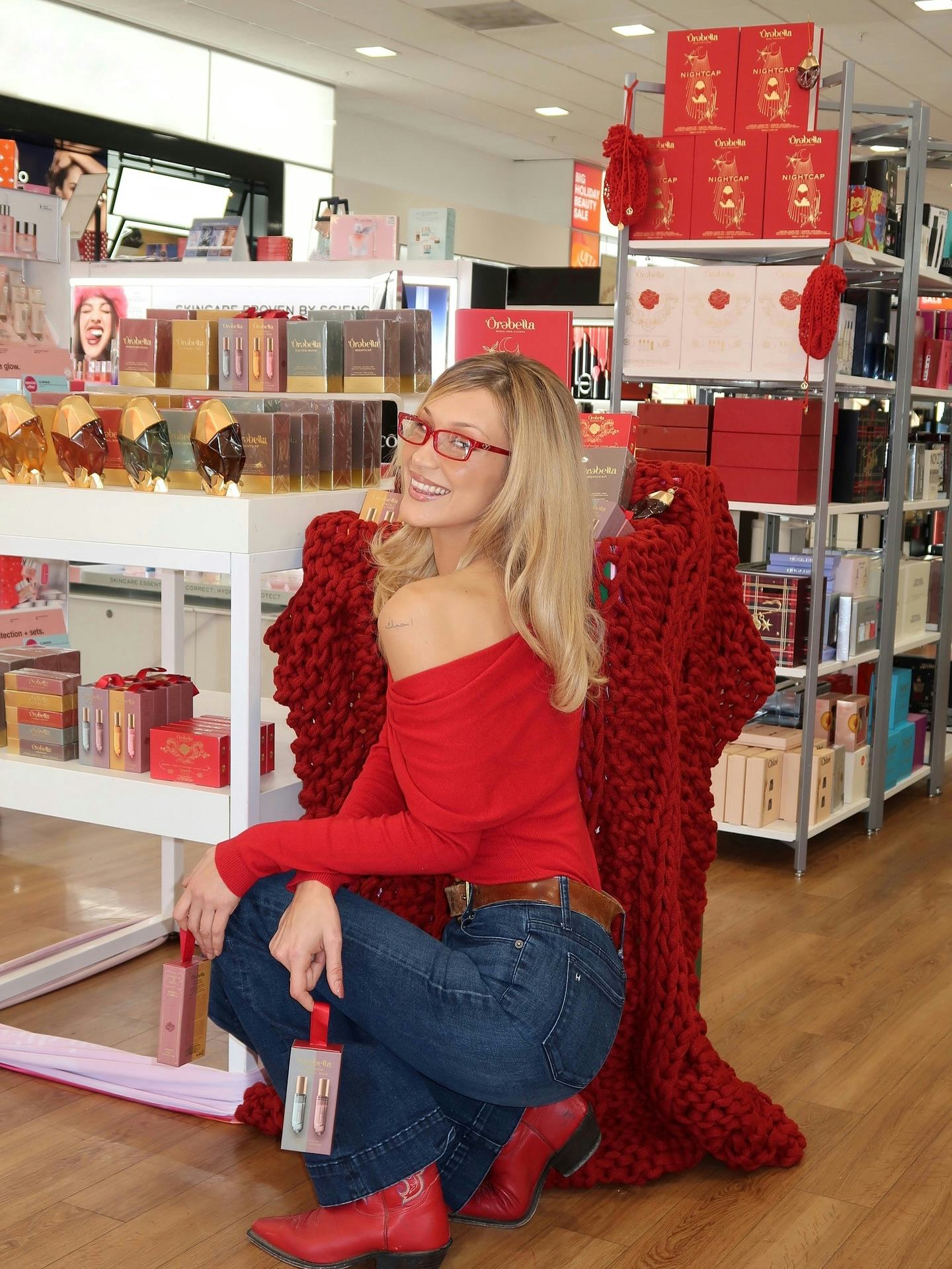 Bella Hadid wears a red off-the-shoulder top and jeans.