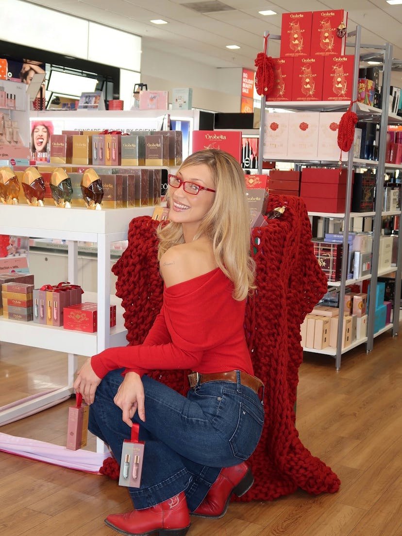 Bella Hadid wears a red off-the-shoulder top and jeans.