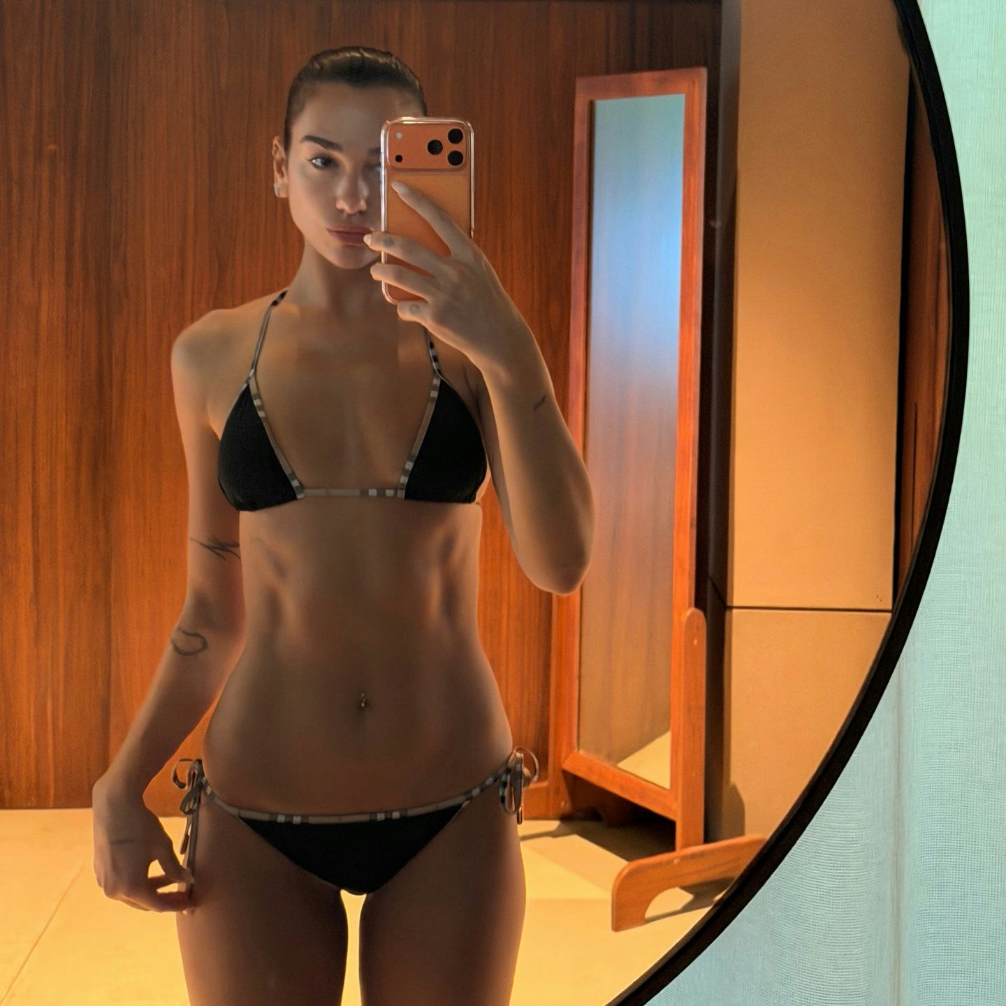 Dua Lipa wears a black bikini. 