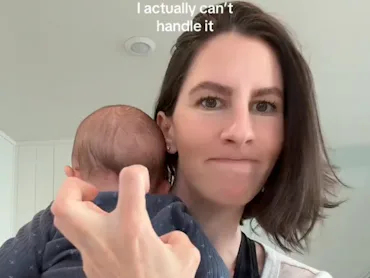 A woman holds a baby in her arms, showing a playful expression while making a hand gesture. The text...