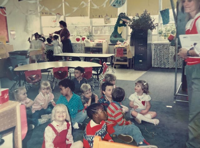 A group of young students sit on the floor of a classroom on Valentine's Day in the early 90s.