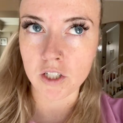 A close-up of a woman with blonde hair and bright blue eyes, wearing a pink shirt. She appears to be mid-sentence, expressing strong emotion.