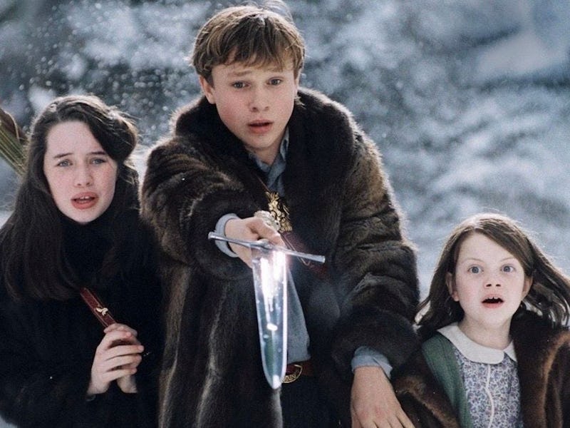 Three children in winter clothing stand against a snowy backdrop, looking determined. One boy holds ...