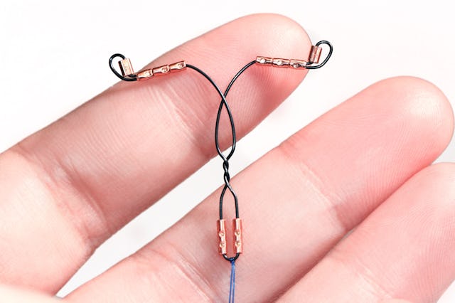 A hand holding a copper IUD.
