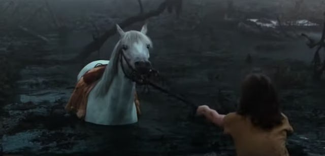 Atreyu, with his back to the camera, attempts to save his horse Artax from drowning in a swamp.