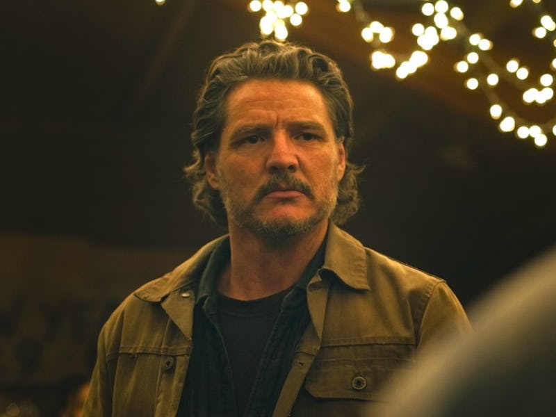 A man with tousled hair and a serious expression stands in a dimly lit space adorned with soft, glow...