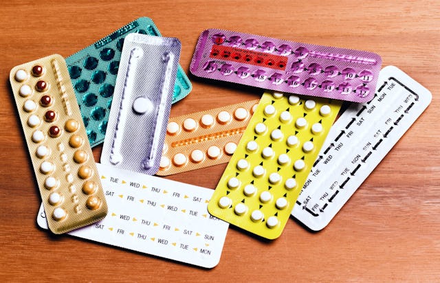 A collection of various birth control pill blister packs in different colors and designs, arranged o...