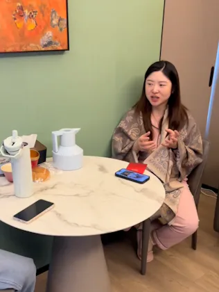 A woman sits at a table, wearing pajamas, in a postpartum hotel in China.