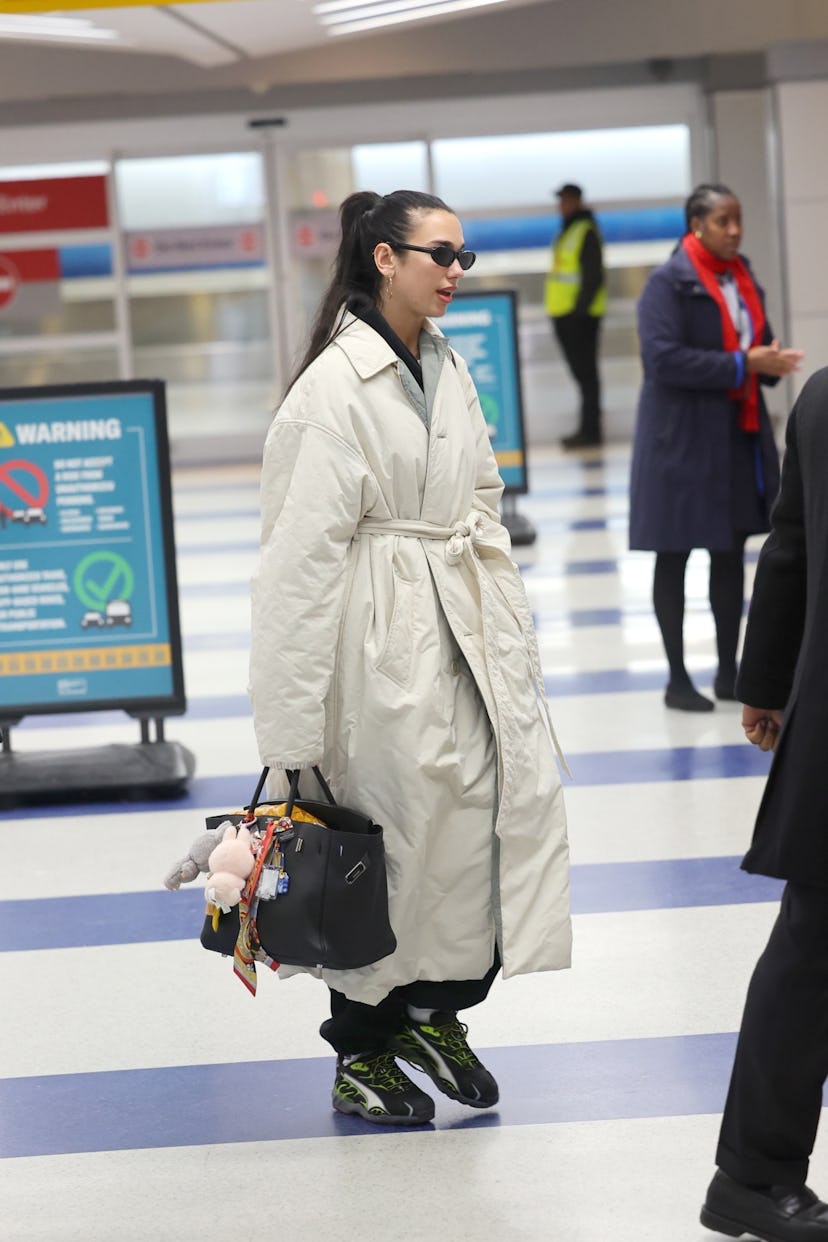 Dua Lipa wears a trench and an Hermès bag.