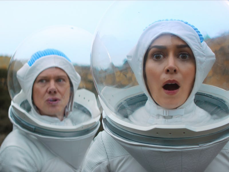 Two astronauts in space suits stand on a rocky terrain, looking surprised. One has a shocked express...