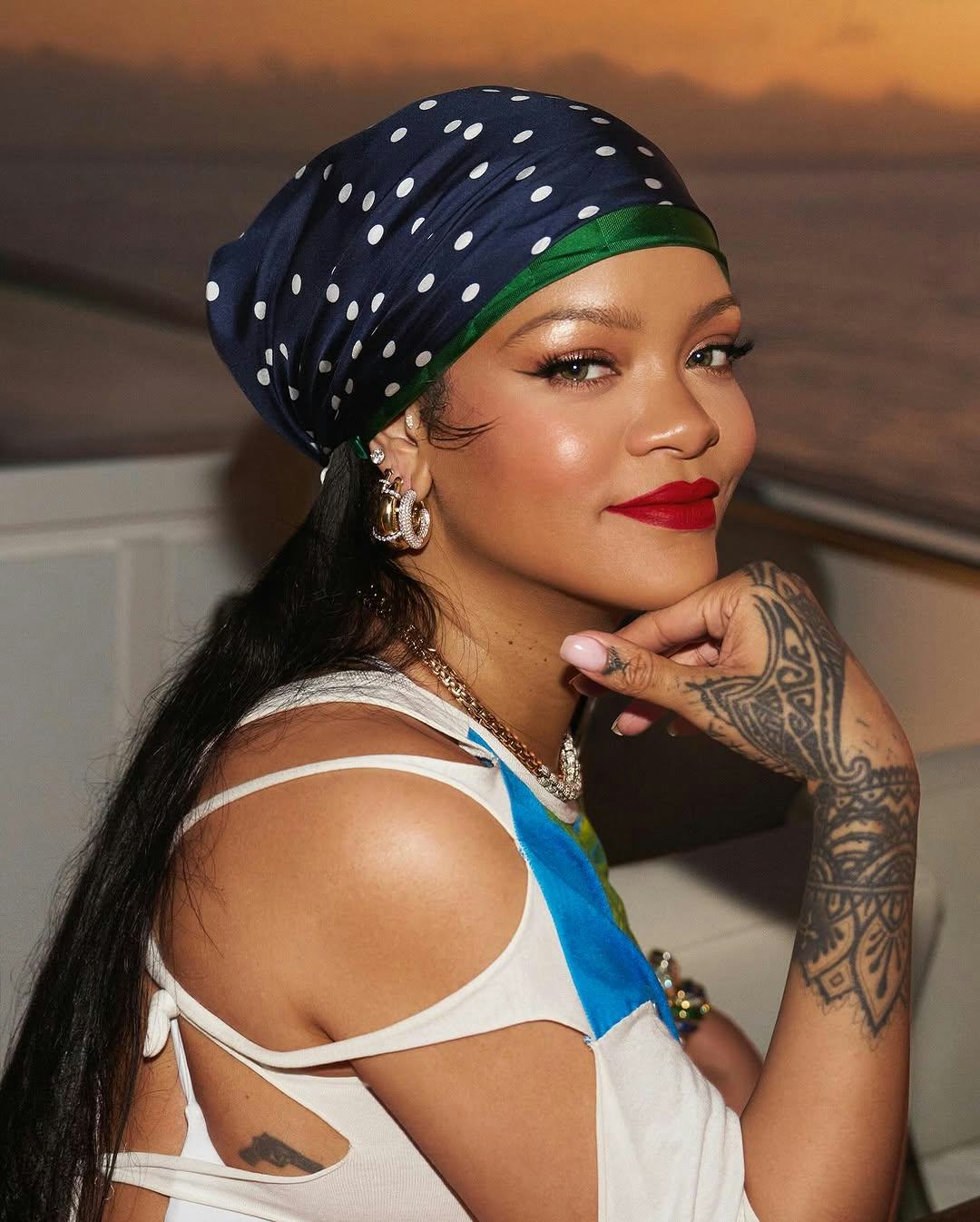 Rihanna wears a white shirt dress with a palm tree print. 