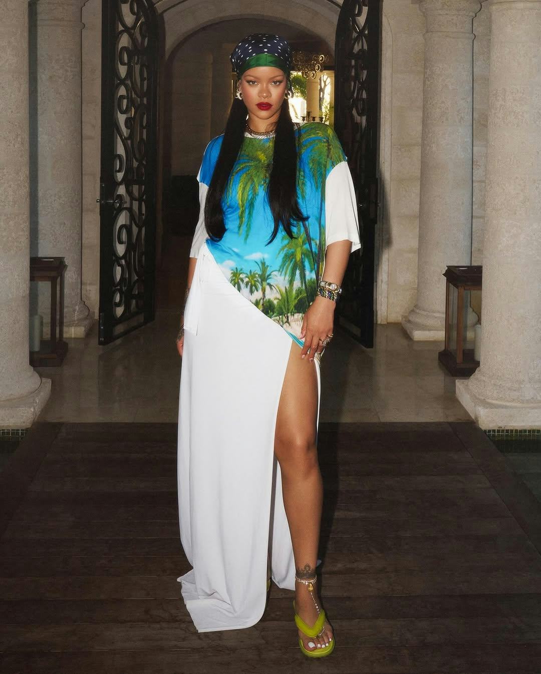 Rihanna wears a white shirt dress with a palm tree print.