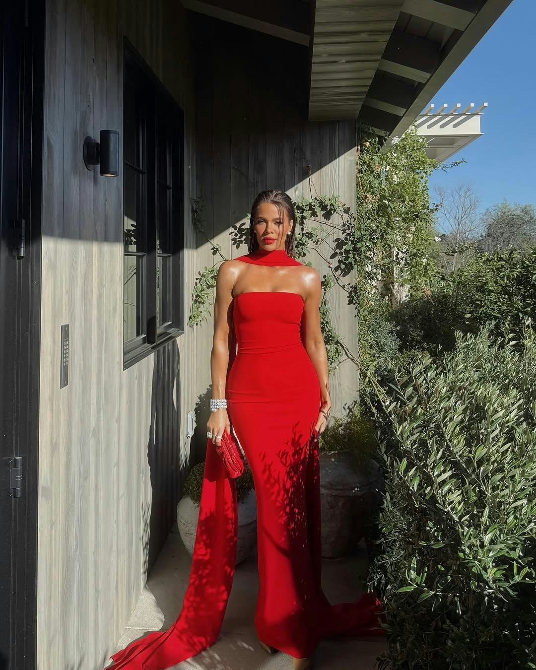 Khloe Kardashian wears a strapless red gown with a scarf.