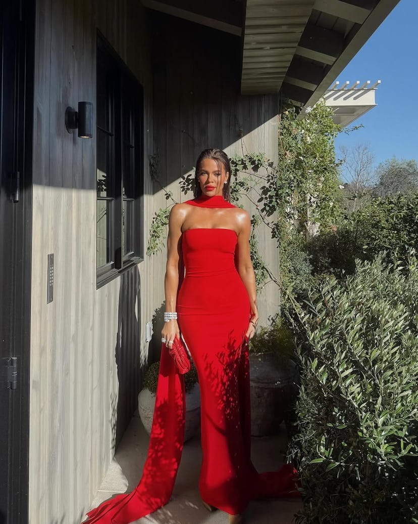 Khloe Kardashian wears a strapless red gown with a scarf.