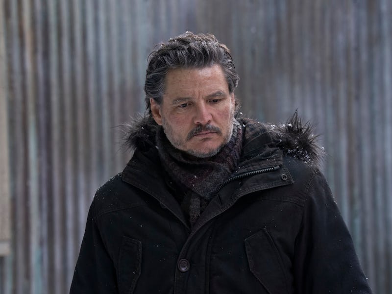 A man with gray hair and a serious expression wears a dark coat and scarf. He stands against a weath...