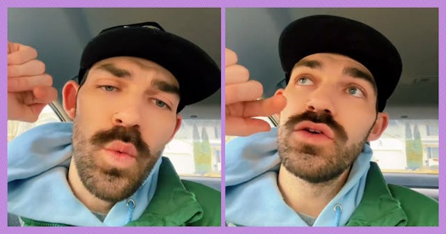 A man with a mustache and beard is sitting in a car. He's wearing a black cap and green jacket, gest...