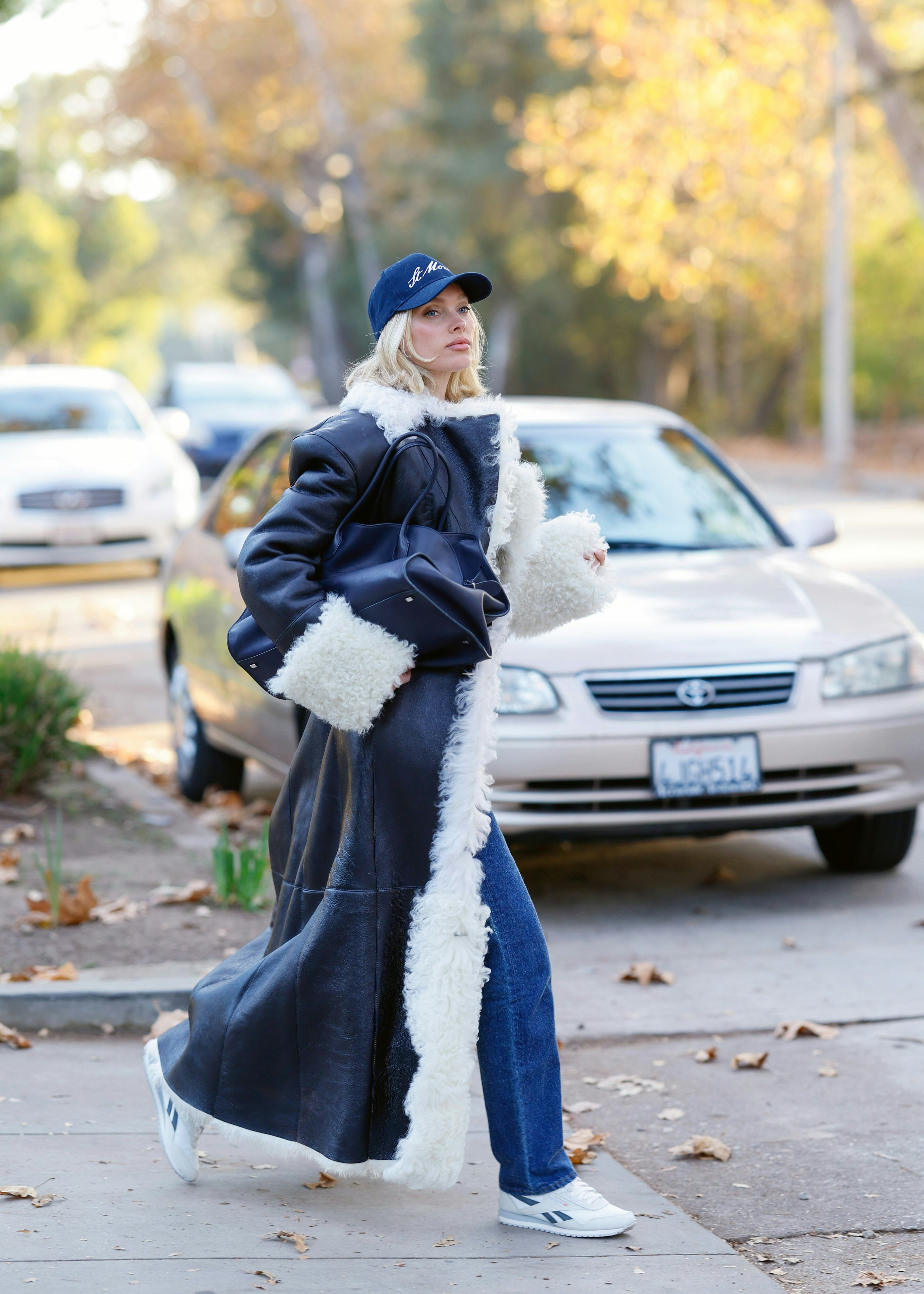 Elsa Hosk wears a fur-trimmed coat, jeans, and Reebok sneakers.