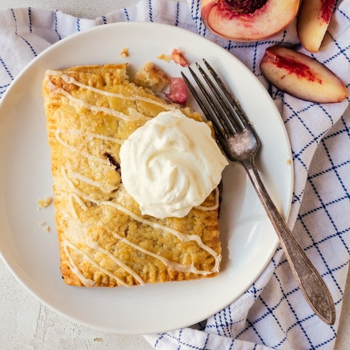 peach hand pie on a white plate with whipped cream on top