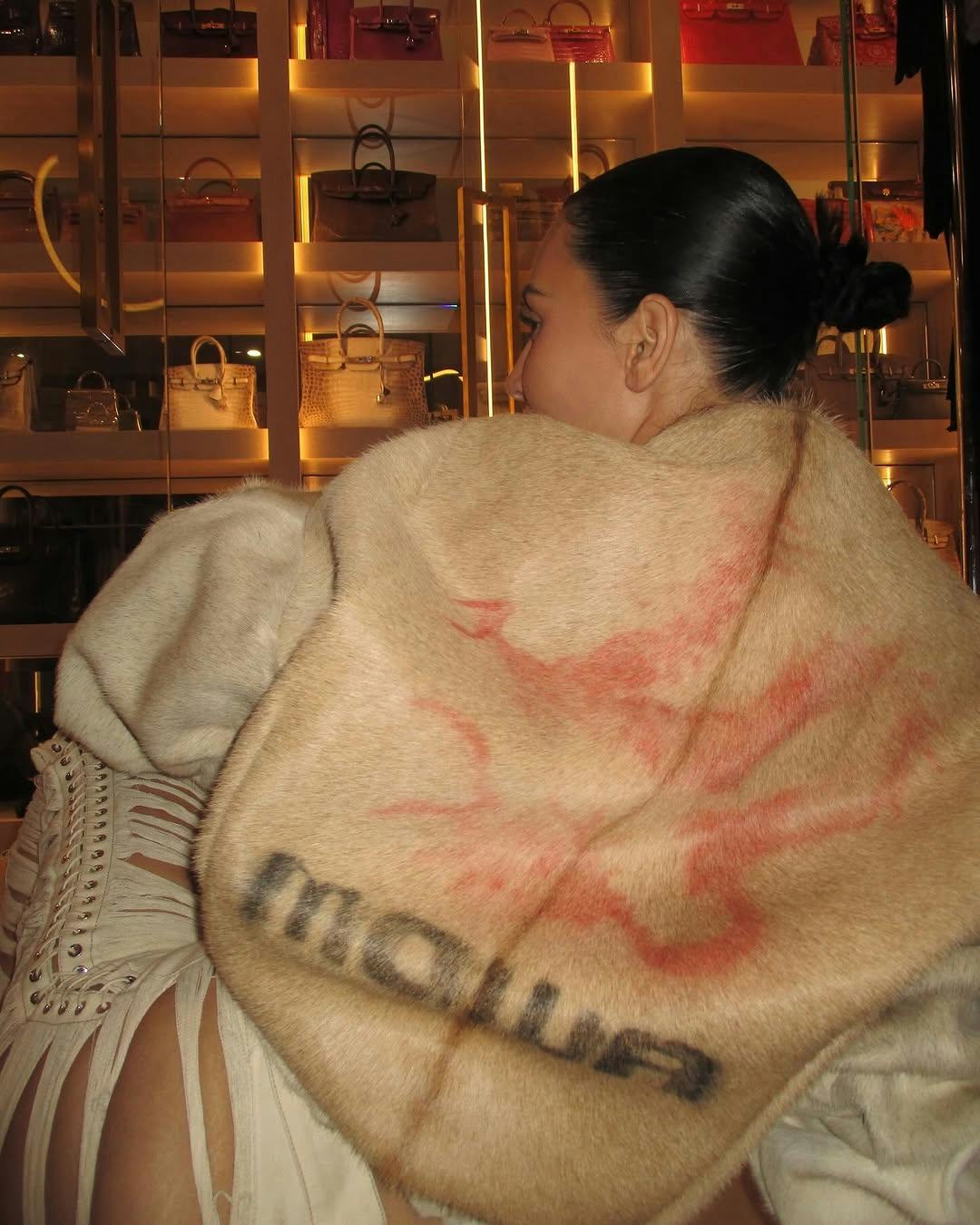 Kim Kardashian wearing a fur coat with assless chaps.