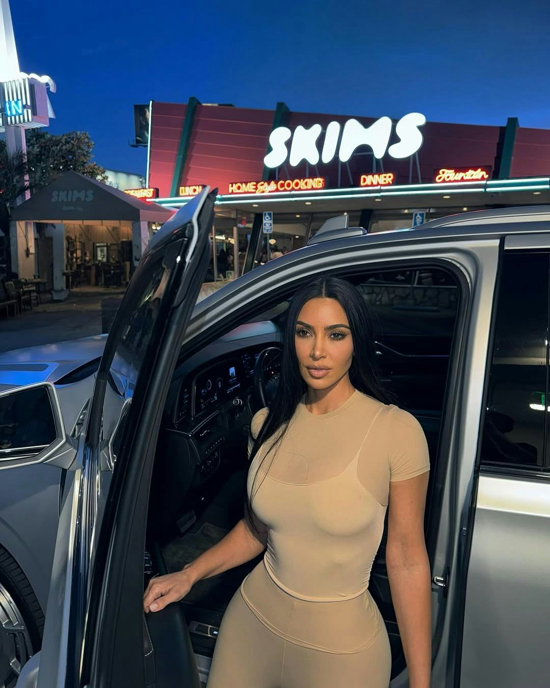 Kim Kardashian wears a beige look with clear heels.