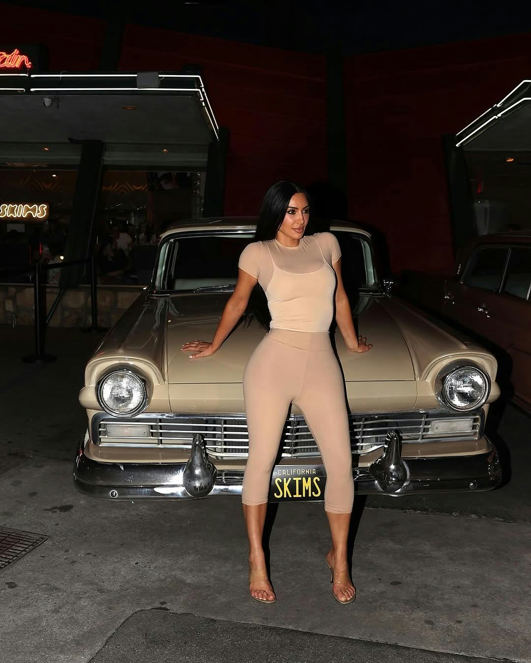 Kim Kardashian wears a beige look with clear heels.