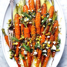 roasted carrots on plate topped with dill, pistachios, and feta, in a story about easter side dishes