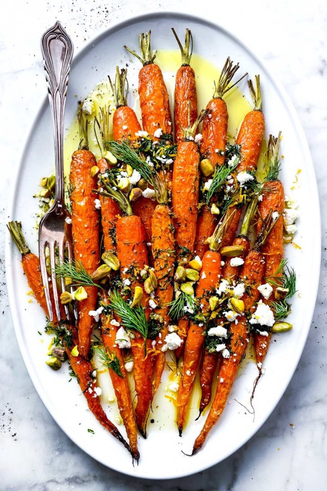roasted carrots on plate topped with dill, pistachios, and feta, in a story about easter side dishes