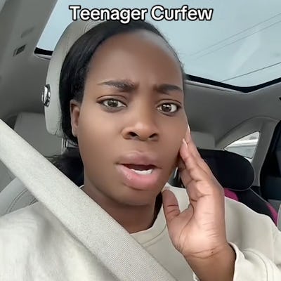 A young woman with dark hair in a car looks surprised or concerned, touching her face. The text above her reads "Teenager Curfew."