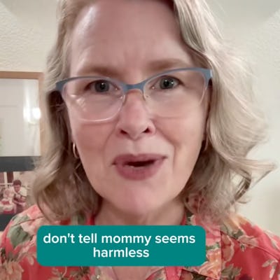 A woman with short, wavy hair and glasses smiles at the camera. She wears a floral shirt. Text overlay reads: "don't tell mommy seems harmless." Background features light-colored walls with framed pictures.