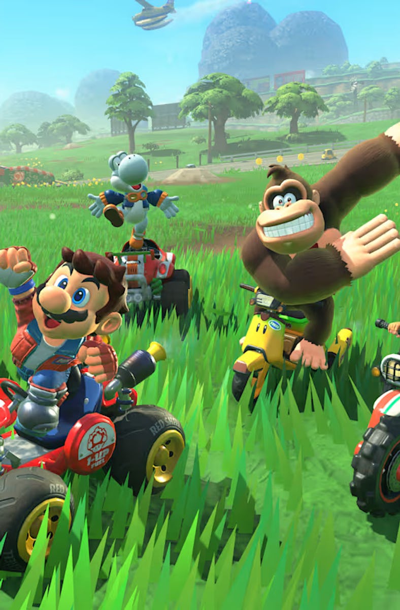 A group of Mario characters on karts in a vibrant green field.
