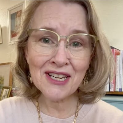 A woman with short blonde hair and glasses smiles warmly at the camera. She wears a light sweater and is in a cozy indoor setting with books. Text on the screen encourages viewers to pause and reflect on three important questions.