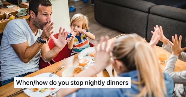 A father and young child sit at a dining table, playfully using hand gestures during dinner, while t...