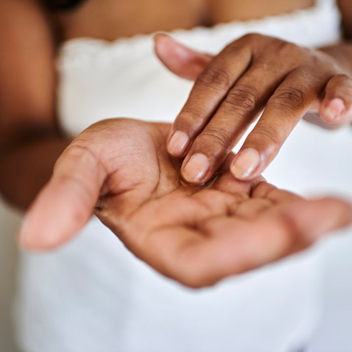 A close-up view of two hands. One hand rests palm-up while the other lightly touches the palm, set a...