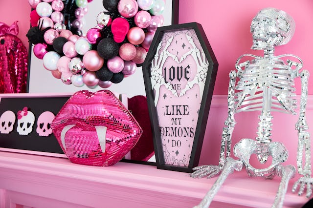 A colorful shelf featuring a shiny pink lip sculpture, a spooky skeleton, a decorative coffin sign, ...