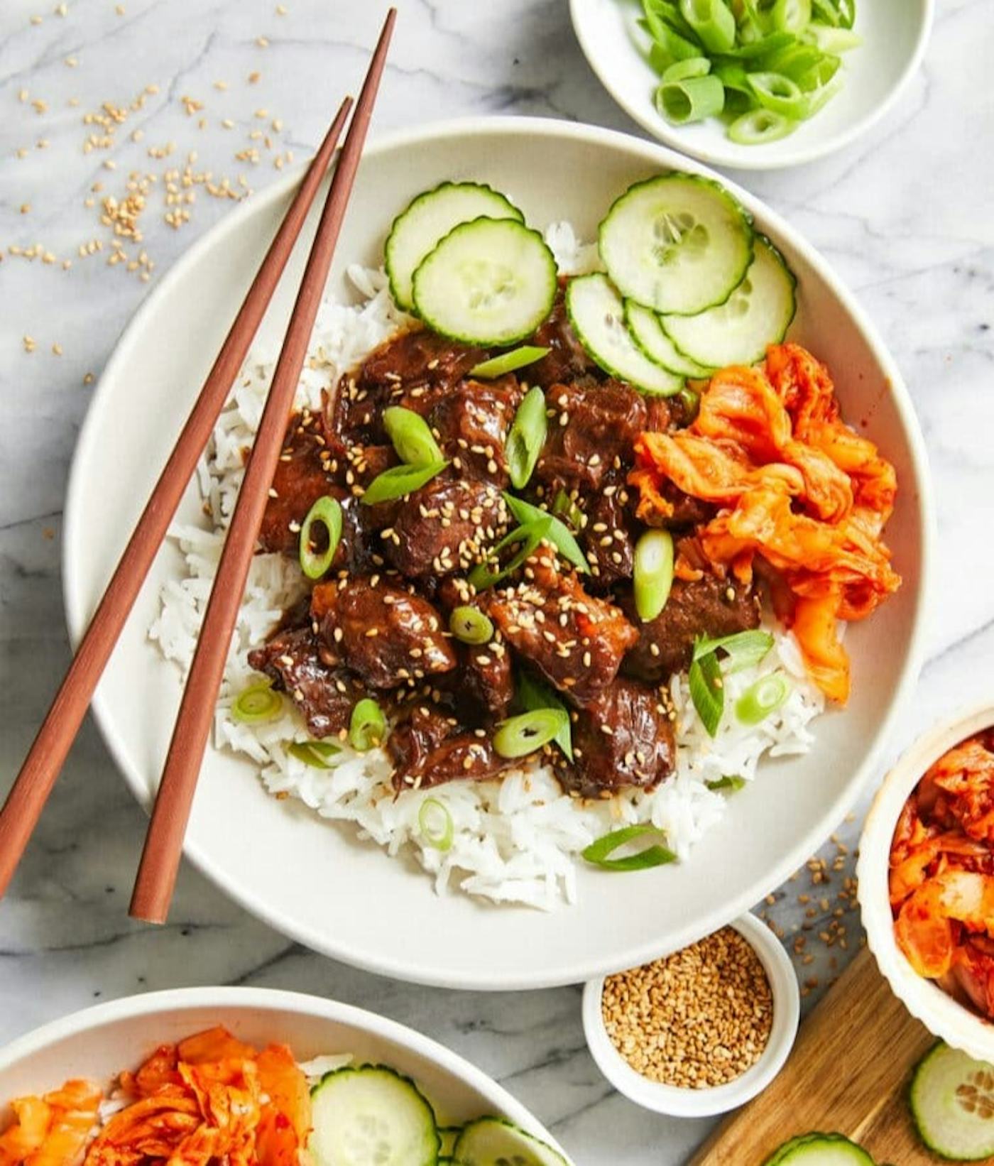 Slow cooker Korean beef in a bowl with rice and cucumbers, in a story about chuck roast recipes.