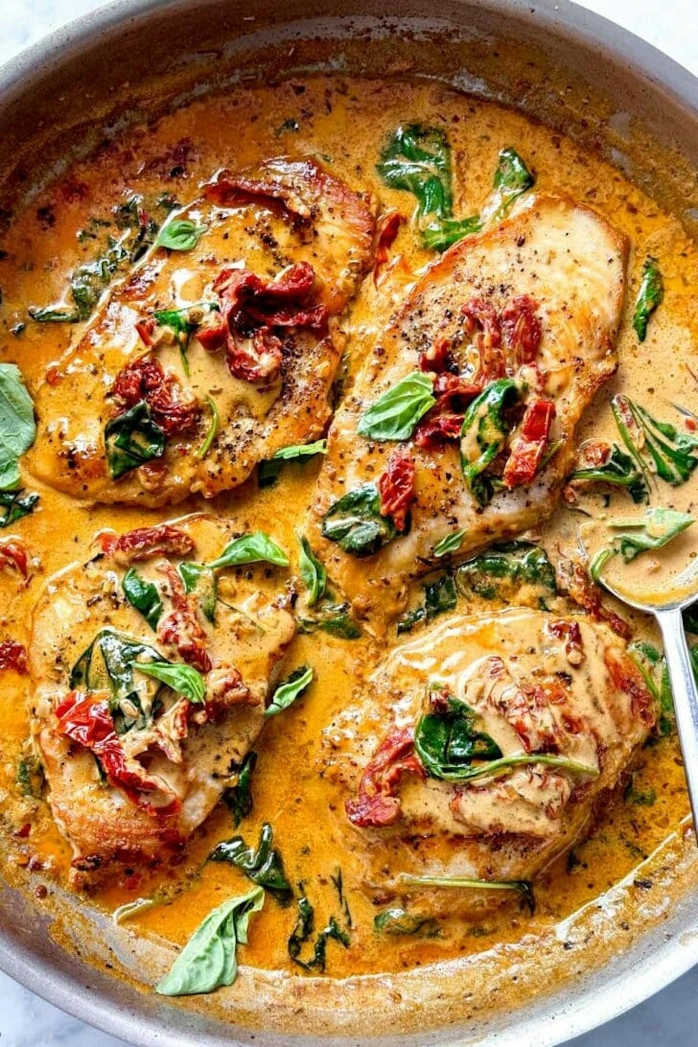 Chicken in sun-dried tomato cream sauce in a skillet, one of many great recipes to use up heavy cream.