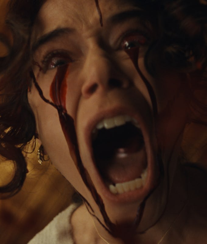 A woman is shown screaming with wide-open eyes, blood streaming from her eyes and down her face, capturing an intense and dramatic moment.